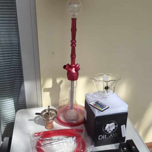 Shisha mit rotem Glas und Zubehör auf Tisch.