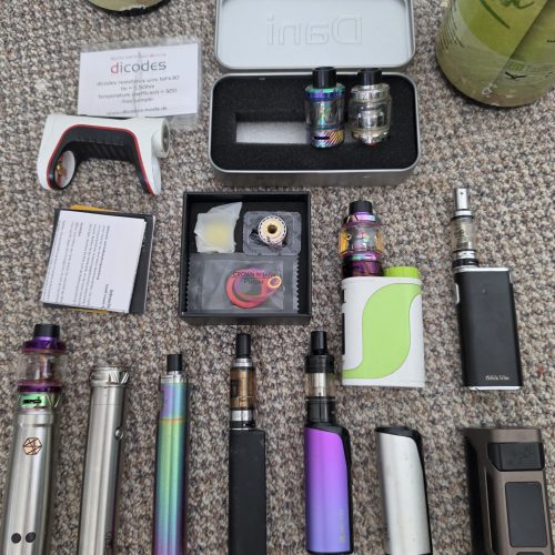 Verschiedene Shisha-Zubehörteile, darunter Glasbowl, Coils und Dampfgeräte.