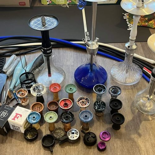 Verschiedene Shisha-Teile, Schläuche, Köpfe und Zubehör auf einem Tisch.