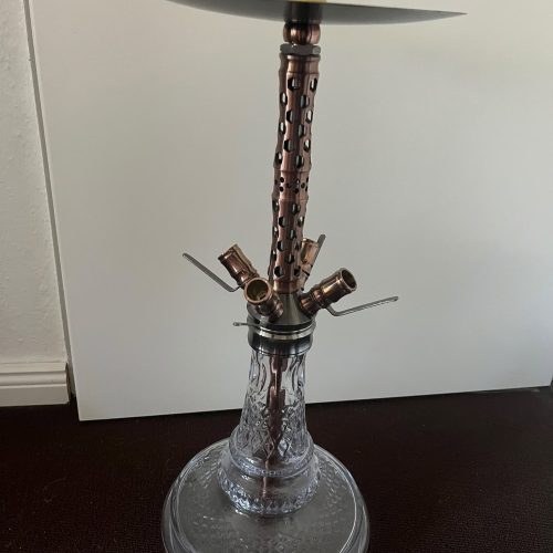 Shisha mit Glasbowl und Metallrohr, auf dunklem Boden.