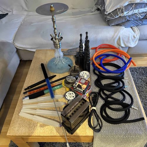 Verschiedene Shisha-Teile, Schläuche und Zubehör auf einem Tisch.