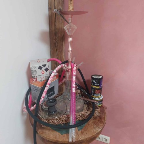 Hookah mit Glasaufsatz, Tabakdosen und Zubehör auf Holzstuhl.