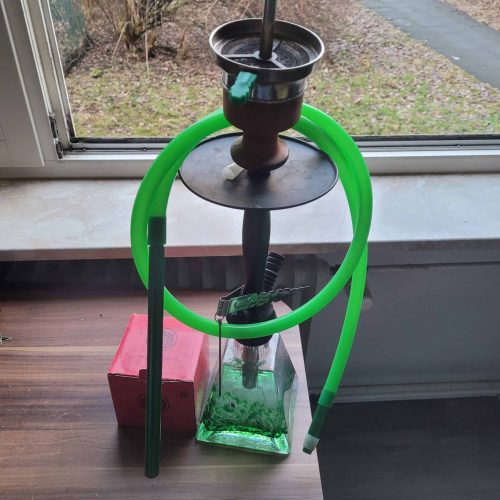 Rauchsäule mit Shisha, Schlauch und Zubehör auf Fensterbank.