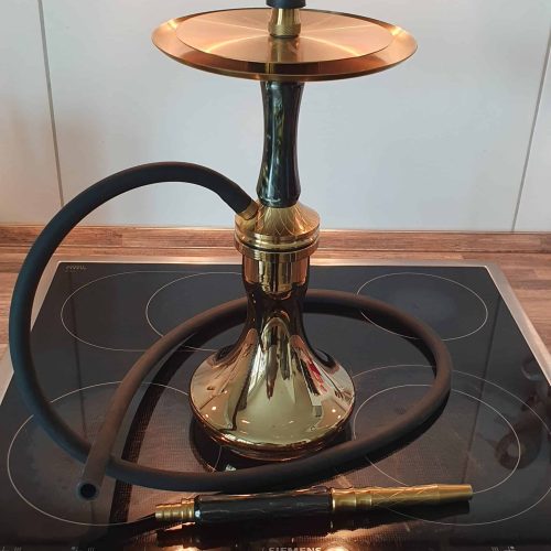 Shisha mit goldener Basis und schwarzem Schlauch auf Herdplatte.