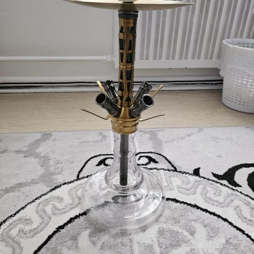 Hookah mit goldener Metallbasis und Glasfuß auf Teppich.