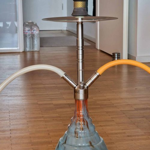 Moderne Shisha mit Glasbowl und Metallteilen auf Holzboden.