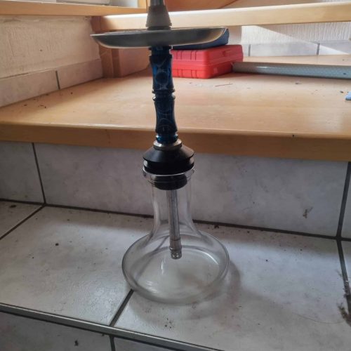 Wasserpfeife mit Rauchsäule auf Fliesenboden.