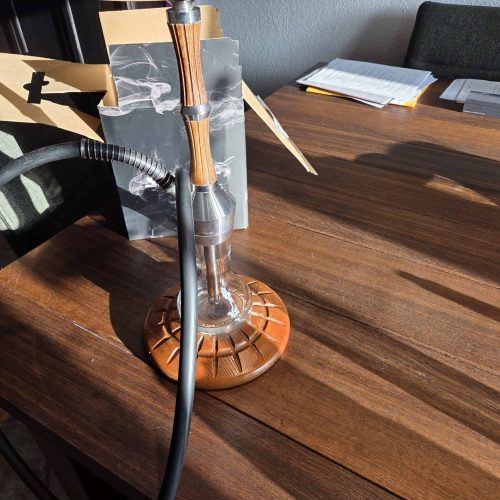 Wasserpfeife mit Glas- und Holzdesign auf einem Tisch.