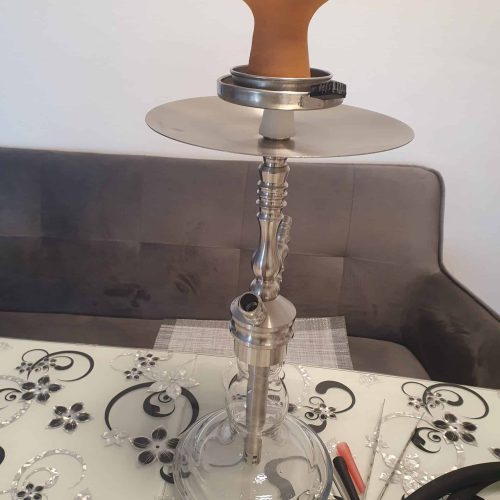 Rauch-Hookah mit Glasbasis und Holzmundstück, auf Esstisch mit Dekoration.