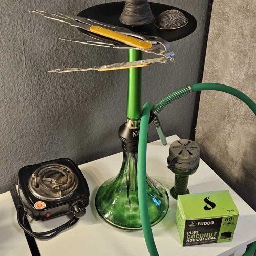 Shisha mit Rauchsäule, Tabak und Zubehör auf Tisch.