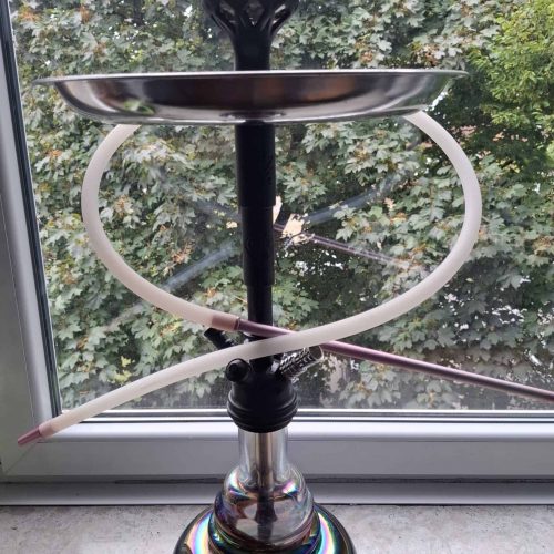Shisha mit Glasbowl, Schlauch und Kopf vor Fenster.
