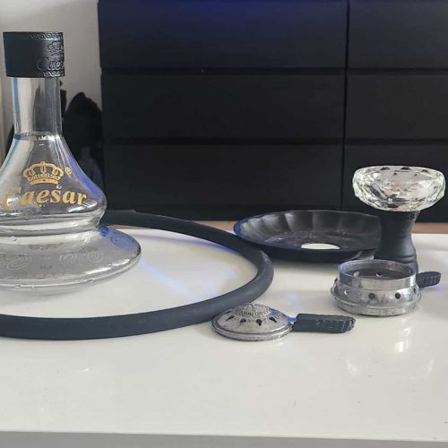 Shisha Zubehör mit Glasbowl, Dampfgerät und Zubehör auf Tisch.