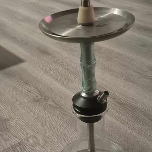 Shisha-Glasbowl mit Metallaufsatz auf Holztisch.