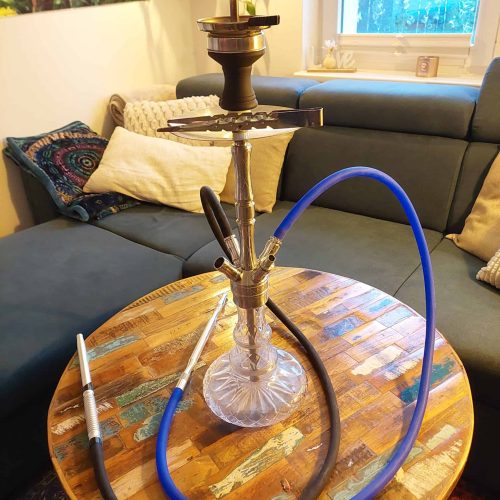 Shisha mit Glasbowl, Schlauch und Tabak auf Holztablett.