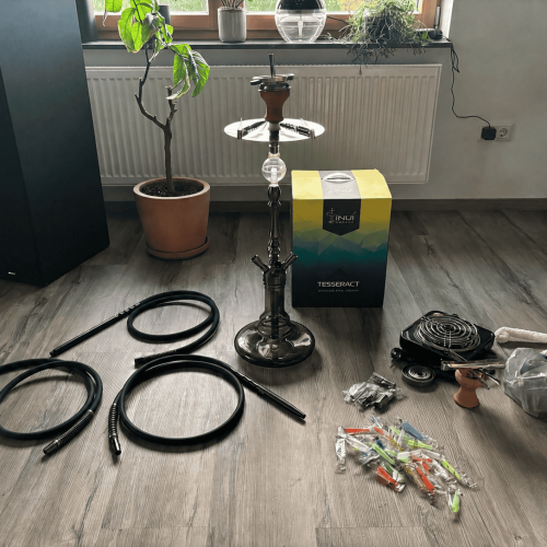 Verschiedene Shisha-Teile, Glasbowl, Schläuche und Zubehör auf Boden.