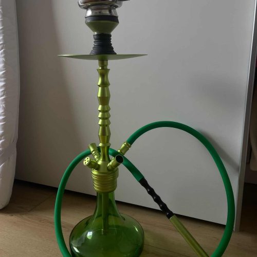 Grüne Shisha mit Glasbowl und Schlauch auf Holzboden.