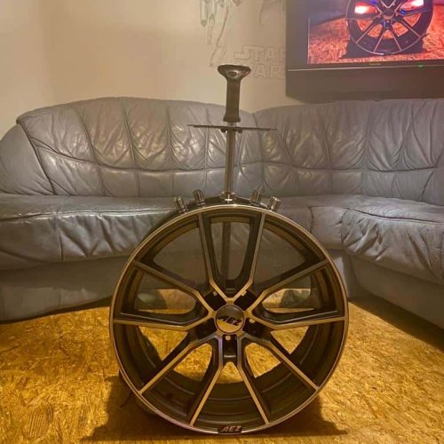 Felge für Auto, schwarz, mit Reifen, auf Holzboden, Wohnzimmer, Nahaufnahme.