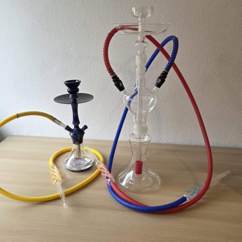 Wasserpfeife mit bunten Schläuchen und Glasaufsatz auf Holztisch.