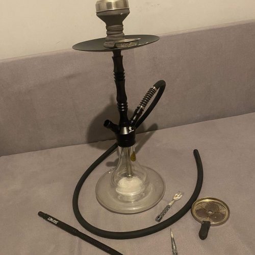 Shisha mit Glasbowl, Schlauch und Zubehör auf Tisch.