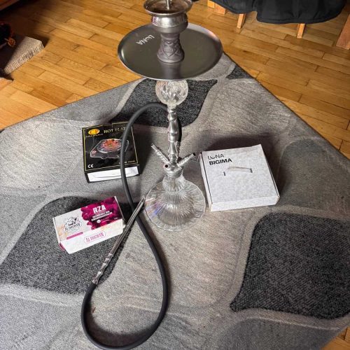 Shisha mit Glasbowl und Zubehör auf Couch.