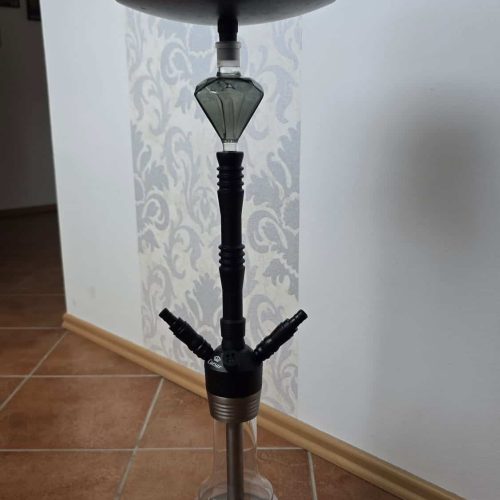 Shisha mit Glasbowl, Schlauch und Kopf, auf Fliesenboden.