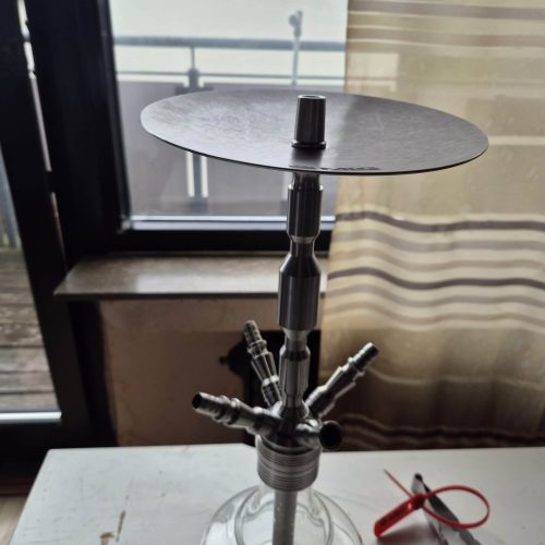 Shisha-Tabakständer mit Glasbowl auf Tisch vor Fenster.
