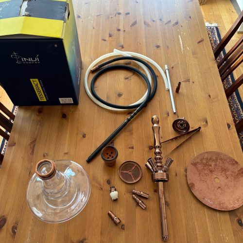 Verschiedene Shisha-Teile und Zubehör auf Holztisch.