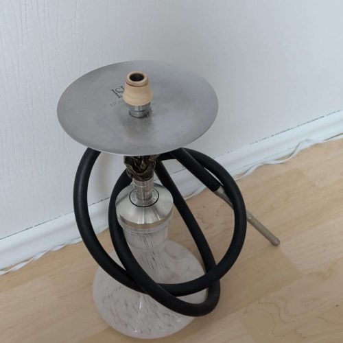 Shisha mit Glasbowl, Schlauch und Kopf auf einem kleinen Tisch.