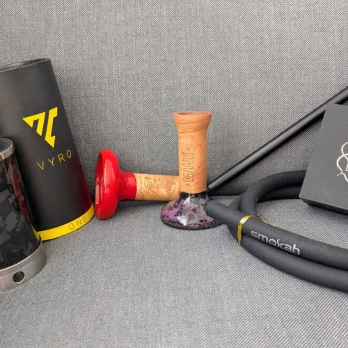 Dampfer, Shisha und Zubehör, inklusive Schlauch, Tabak und Kohle, auf einer Couch.