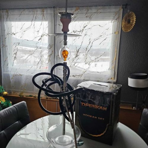 Rauchsäule mit Shisha-Set auf einem Tisch, inklusive Glas, Schlauch und Zubehör.