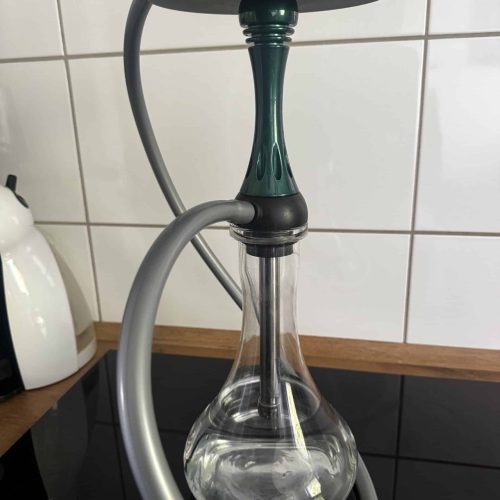 Shisha mit Glasbowl, Silikonschlauch und Metallaufsatz auf Tisch.