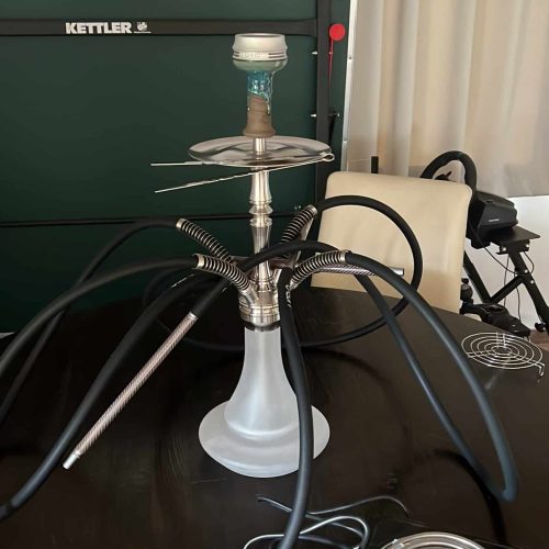Rauchsäule mit Shisha, Heizgerät und Zubehör auf Tisch.