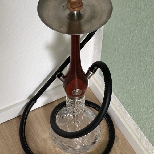 Rauchende Wasserpfeife mit Glasbowl, Metallaufsatz und Schlauch, ideal für Shisha-Liebhaber.