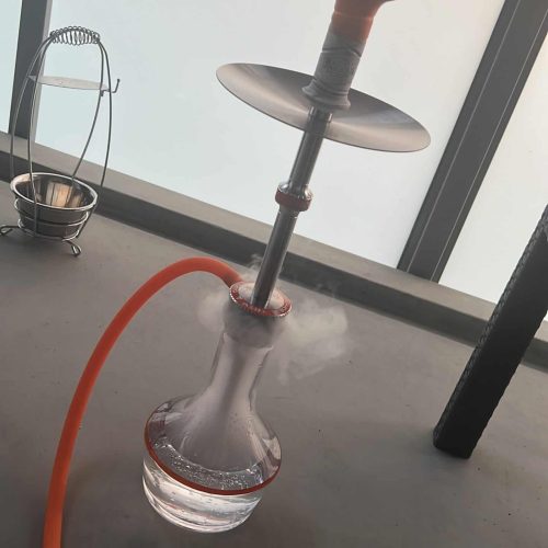 Shisha mit Glasbowl und Silikonschlauch auf Tisch.