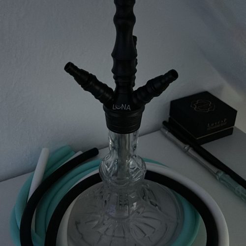Rauchsäule mit Shisha-Kopf, Schlauch und Zubehör auf einem Tisch.
