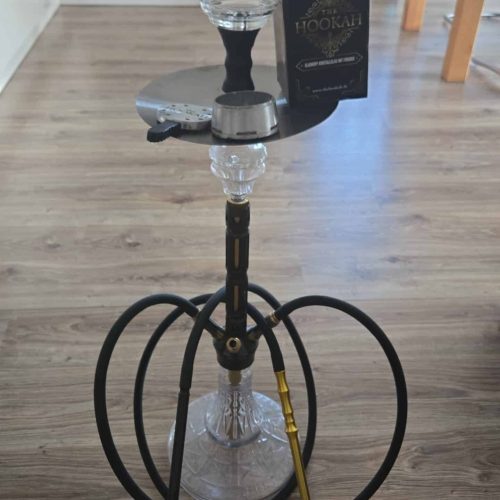 Rauch-Hookah auf einem Holztisch mit Zubehör und Verpackung im Hintergrund.