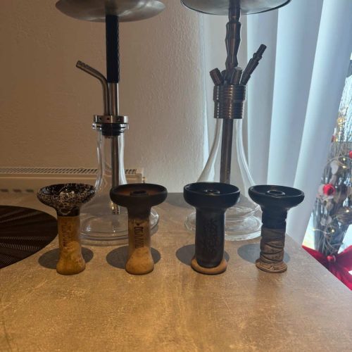 Zwei Shisha-Köpfe mit verschiedenen Schläuchen und Zubehör auf einem Tisch.
