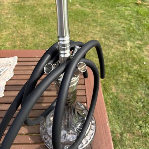 Moderne Shisha mit Glasbowl, Metallrohr und Schlauch auf Holztisch.