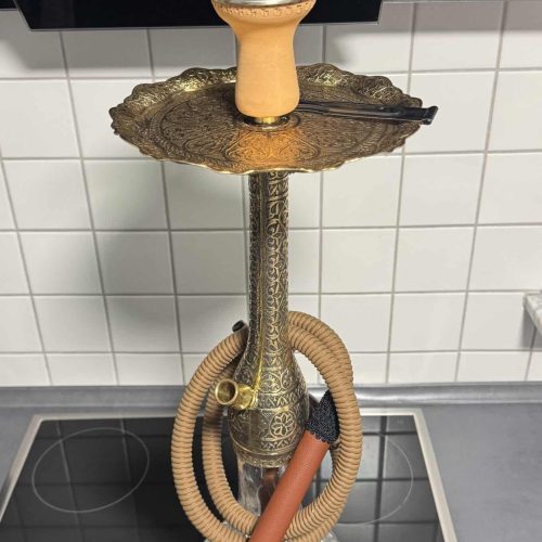 Alte Shisha mit Glasbowl und Zubehör auf Herdplatte.
