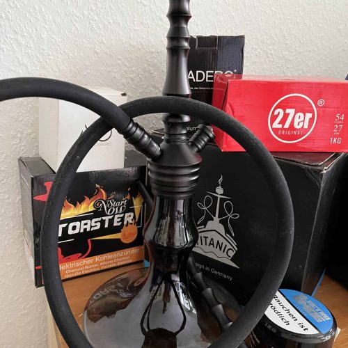Shisha mit Rauchrohr und Zubehör auf Tisch.