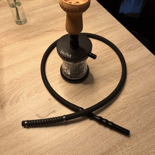 Shisha mit Keramik-Bowl, Glasbowl und flexiblem Schlauch auf Holztisch.