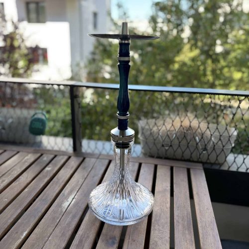 Shisha-Kopf mit Glasbowl auf Holztisch, Balkon mit Stadtblick im Hintergrund.