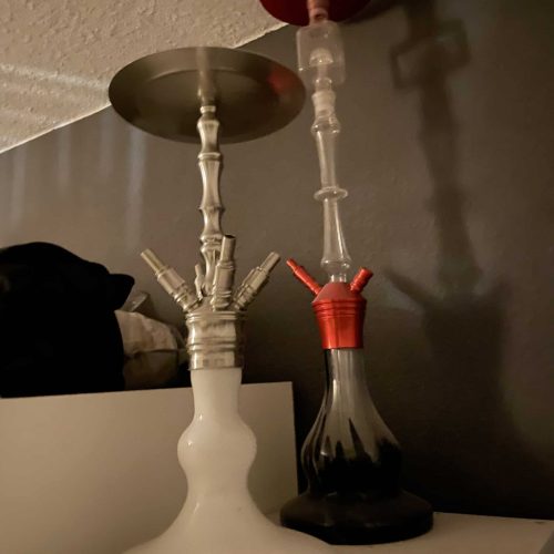 Zwei Shishas auf einem Tisch, eine weiße und eine schwarze, mit Rauch.