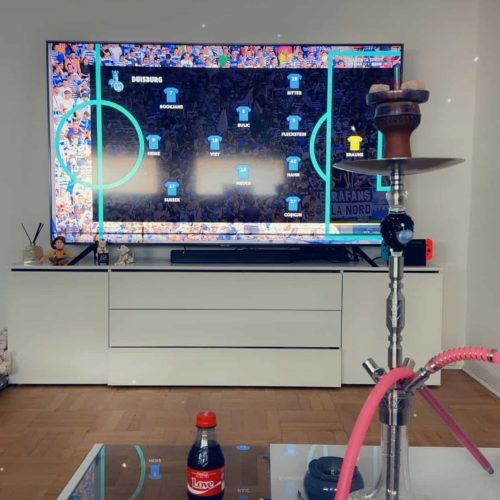 Großer Fernseher mit Apps und buntem Rahmen, Shisha auf Tisch im Vordergrund.