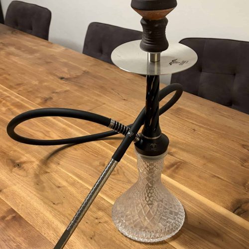 Hookah mit Glasbasis, Metallhaken und Holzkopf auf Holztisch.