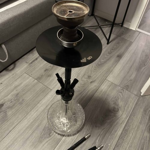 Rauchsäule mit Shisha, Wasserpfeife und Zubehör auf Boden in Wohnzimmer.