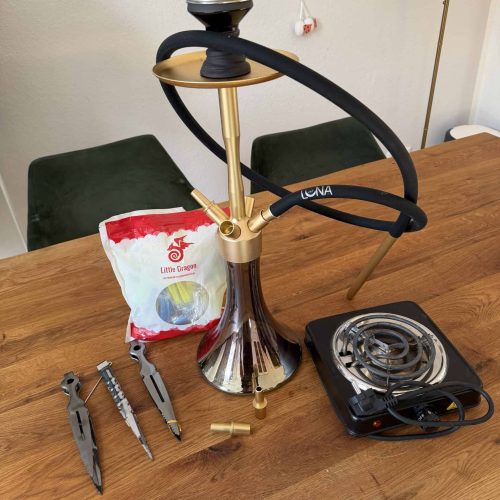 Shisha mit Glasbowl, Heizplatte und Werkzeugen auf Tisch.