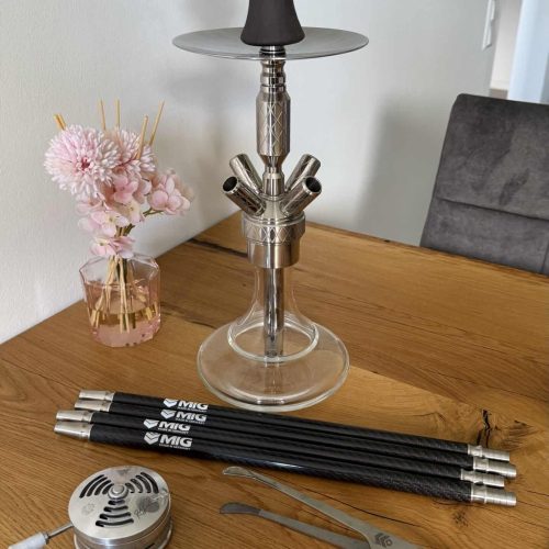 Rauchsäule mit Zubehör, inklusive Tabak, Kohle und Zange, auf einem Holztisch.