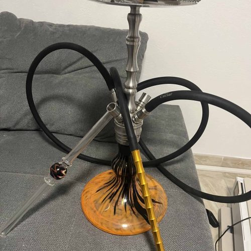 Shisha mit Metall- und Glas-Design, auf einem Sofa stehend, bereit zum Rauchen.