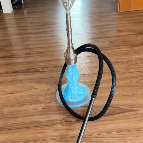 Shisha mit blauer Glasbowl, Metallstange und Schlauch auf Holzboden.